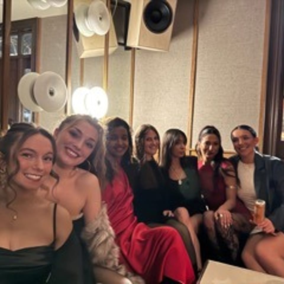 Group of smiling women posing together in a warmly lit restaurant lounge.