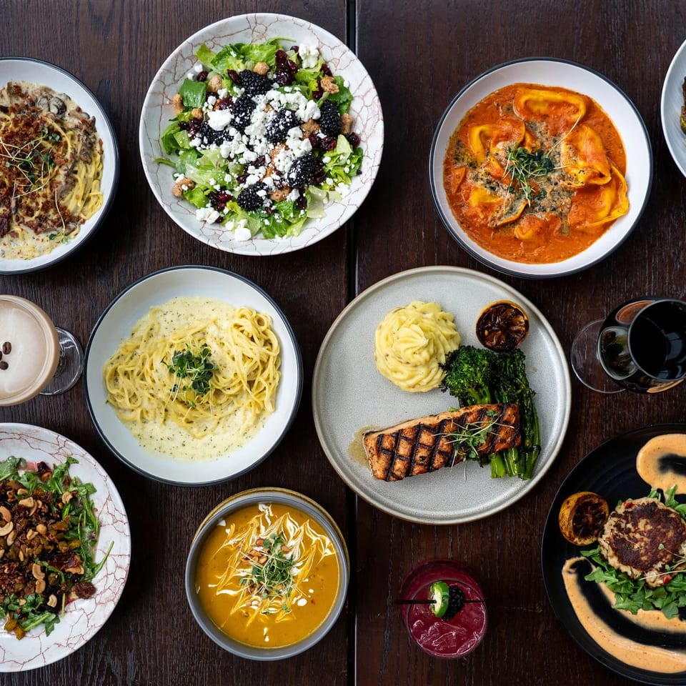 Overhead view of a dark wooden table laden with various Italian dishes, drinks, and desserts.